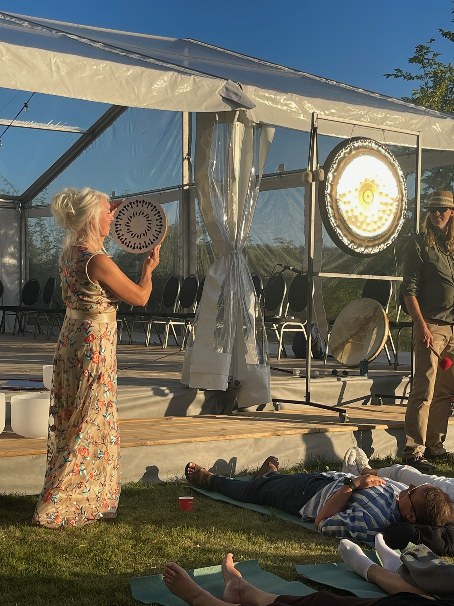Aurelina performing beside crystal singing bowls and a gong outdoors at Hälsofestivalen Wenngarn